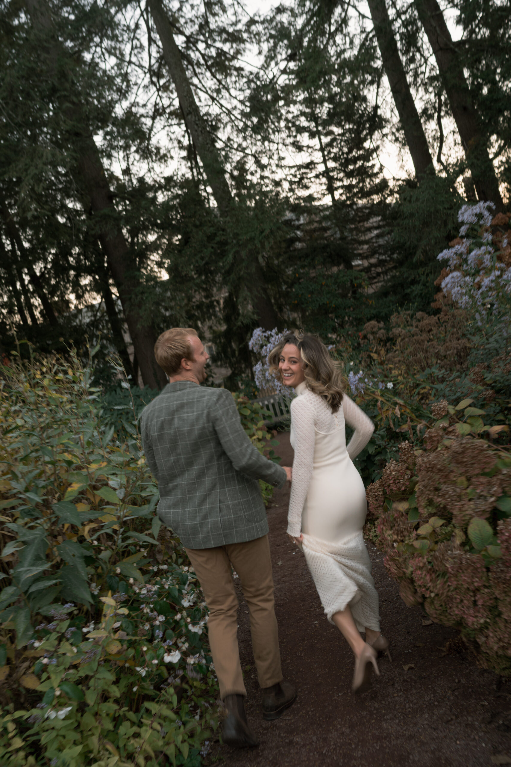 Couple runs through gardens at Princeton University at dusk.